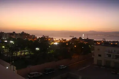 a view of a city at night with a lighthouse at Golden Rose Hotel in Aqaba