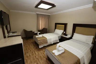 a hotel room with two beds and a flat screen tv at Al Zaitouna Hotel in Aqaba