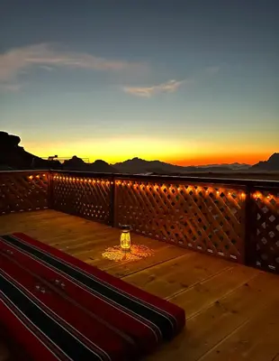 a bench on a deck with a sunset in the background at Desert Magic Camp & Resort in Wadi Rum