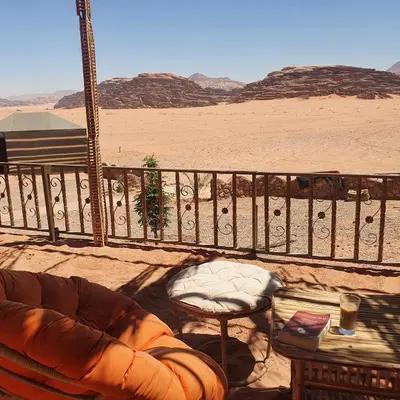 a balcony with a couch and a table in the desert at Desert Magic Camp & Resort in Wadi Rum