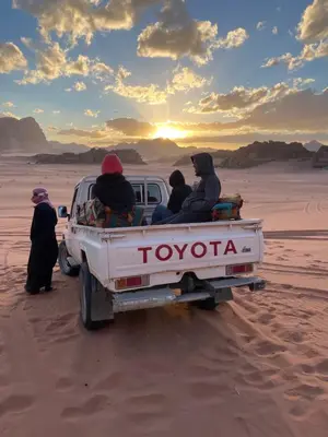 a group of people in the back of a truck in the desert at North moon Camp in Wadi Rum