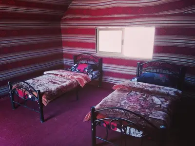 a room with two beds and a window at Wadi Rum Old Bedouin Camp in Wadi Rum