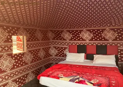 a bed in a room with a red wall at Wadi Rum Bright Moon in Wadi Rum