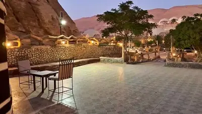 a patio with a table and chairs and a stone wall at Seven Wonders Luxury Camp in Wadi Musa