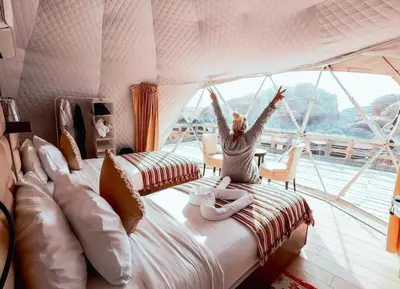 a woman is sitting on a bed on a boat at Seven Wonders Luxury Camp in Wadi Musa