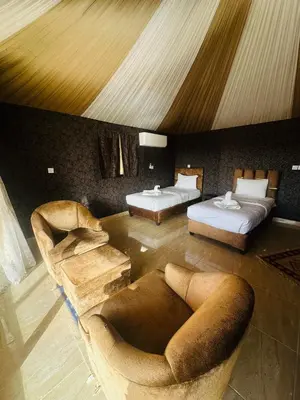 a living room with two beds and two chairs at domes wadi Rum in Wadi Rum