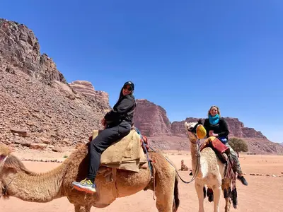 two people riding on the backs of camels in the desert at Wadi rum Silk Road camp in Wadi Rum
