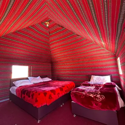 two beds in a room with a red striped wall at Wadi rum Silk Road camp in Wadi Rum
