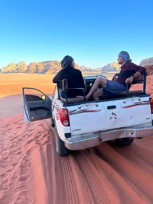two people sitting in the back of a car in the desert at Wadi rum Silk Road camp in Wadi Rum