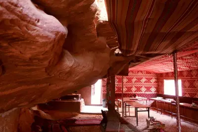 a room with a rock wall and tables and chairs at Sunrise camp in Wadi Rum