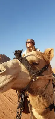 a man riding on the back of a camel in the desert at Sunrise camp in Wadi Rum