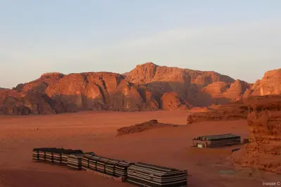 a desert with red rocks and wooden fences at Sunrise camp in Wadi Rum