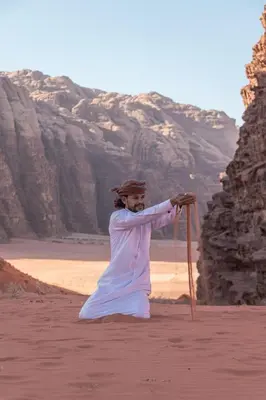a woman standing on a beach holding a stick at Wadi Rum Pyramids Camp in Wadi Rum