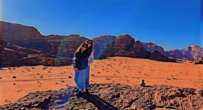 a woman standing on a rock in the desert at Landscape Rum Camp in Wadi Rum