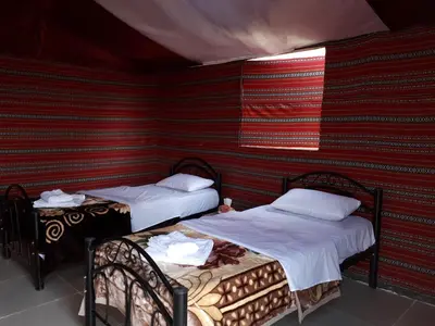 two beds in a room with a red wall at Landscape Rum Camp in Wadi Rum