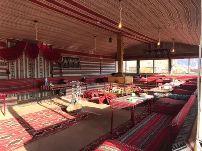 a large room with red chairs and tables and windows at Omar Ghazi Camp in Wadi Rum