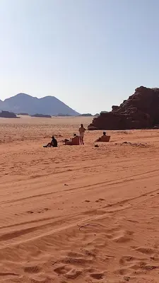 a group of people sitting on a sandy beach at Omar Ghazi Camp in Wadi Rum