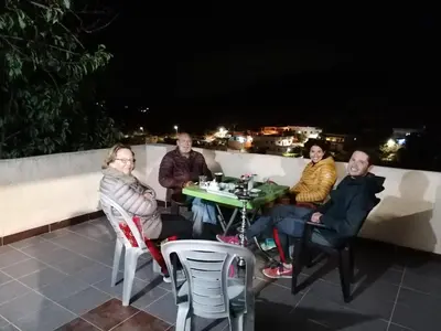 a group of people sitting at a table on a roof at Mhna guest house بيت الضيافة الريفي in Ajloun