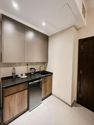 a kitchen with wooden cabinets and a black counter top at Celino Hotel in Amman