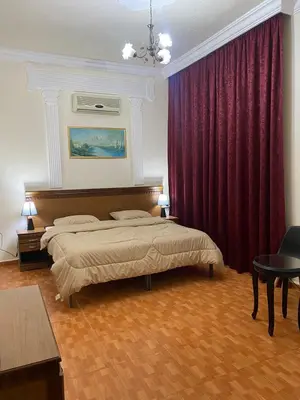 a bedroom with two beds and red curtains at Sufara Hotel Suites in Amman