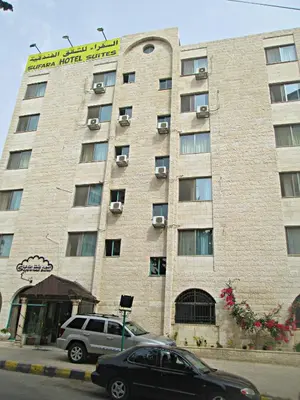 a large building with cars parked in front of it at Sufara Hotel Suites in Amman