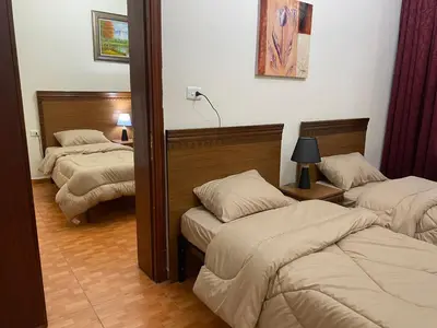 a room with three beds in a room at Sufara Hotel Suites in Amman