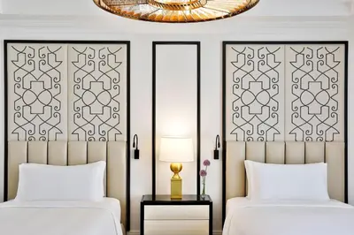 a bedroom with two beds and a chandelier at The St. Regis Amman in Amman