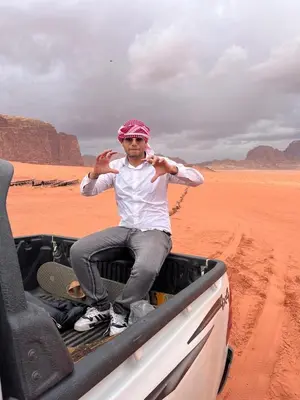 a man sitting in the back of a truck in the desert at Moon city camp in Wadi Rum