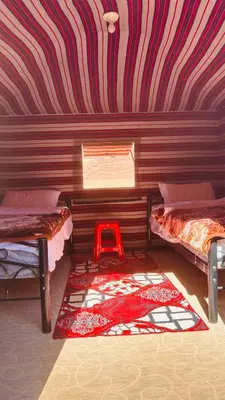 a room with two beds and a red stool in it at Desert guide camp in Wadi Rum