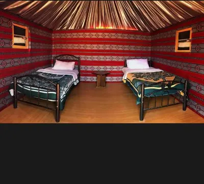 a room with two beds in a red room at Desert guide camp in Wadi Rum