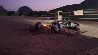 a group of people sitting around a fire on the beach at Desert guide camp in Wadi Rum