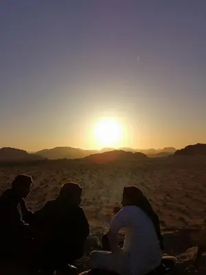 three people sitting in the desert watching the sunset at Desert guide camp in Wadi Rum