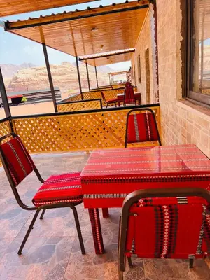 a red table and two chairs on a patio at wadi rum bedouin stars camp in Wadi Rum