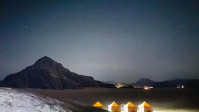 a group of tents on a beach at night at Rum Jordan camp and tours in Wadi Rum