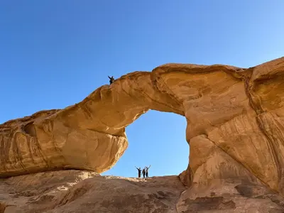 people standing on an arch in the desert at Rum Jordan camp and tours in Wadi Rum