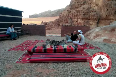 a group of people sitting around a fire in the desert at Wadi Rum Desert Base Camp in Wadi Rum