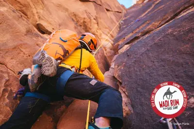 a man is climbing on a rock formation at Wadi Rum Desert Base Camp in Wadi Rum