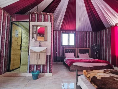 a room with two beds and a sink in a tent at Beduin Star Trail Camp in Wadi Rum