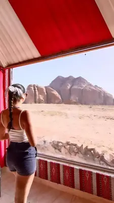 a woman looking out of a window at the desert at Beduin Star Trail Camp in Wadi Rum