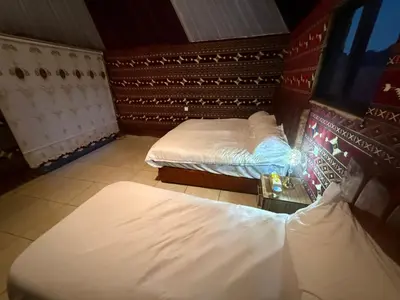a room with two beds and a tv in it at Khazali Mountain Camp in Wadi Rum