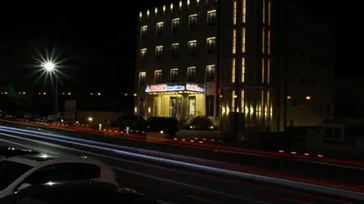 a building at night with cars parked in front of it at Big Ben Hotel Suites in Amman