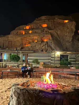 a fire pit in front of a rock formation at Taj Wadi Rum camp in Wadi Rum