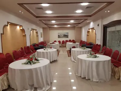 a conference room with tables and red chairs at Amman Ambiance Hotel in Amman