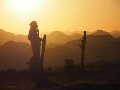 a woman standing on top of a hill at sunset at Wadi Rum Moon Camp in Wadi Rum