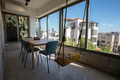 a dining room with a table and chairs and windows at Battuta Hostel in Amman