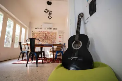 a guitar sitting on a couch in a room with a table at Battuta Hostel in Amman