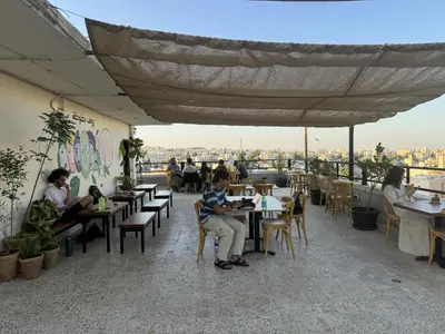 a group of people sitting at tables in a restaurant at Battuta Hostel in Amman