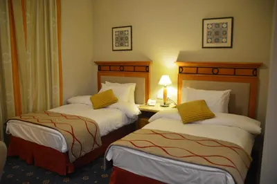 a hotel room with two beds and a table with a lamp at The Y Hotel in Amman