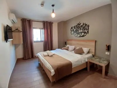 a bedroom with a large bed and a tv at Layaali Amman Hotel in Amman