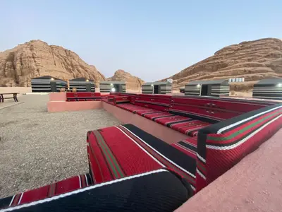 a group of red benches in front of some mountains at مخيم الجبال البرونزية in Wadi Rum